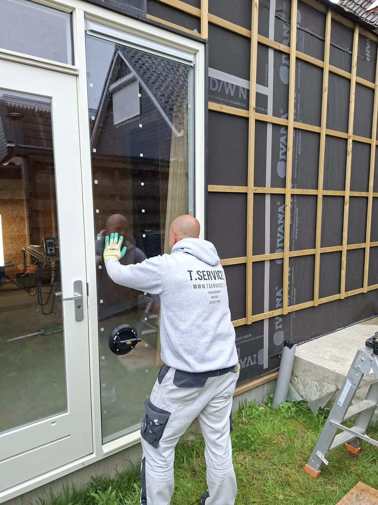 T. Services tijdens glasplaatsing in een nieuwe aanbouw